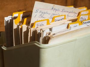 A vintage recipe box filled with handwritten and typed recipe cards organized with tabbed dividers