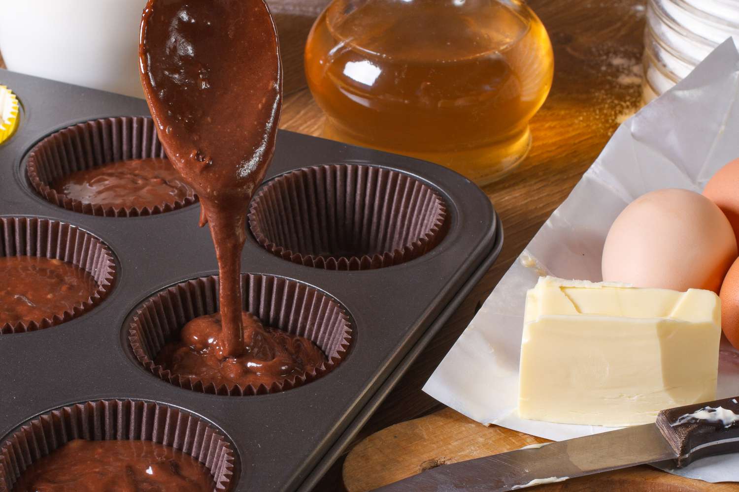 Chocolate batter being portioned into a muffin tin