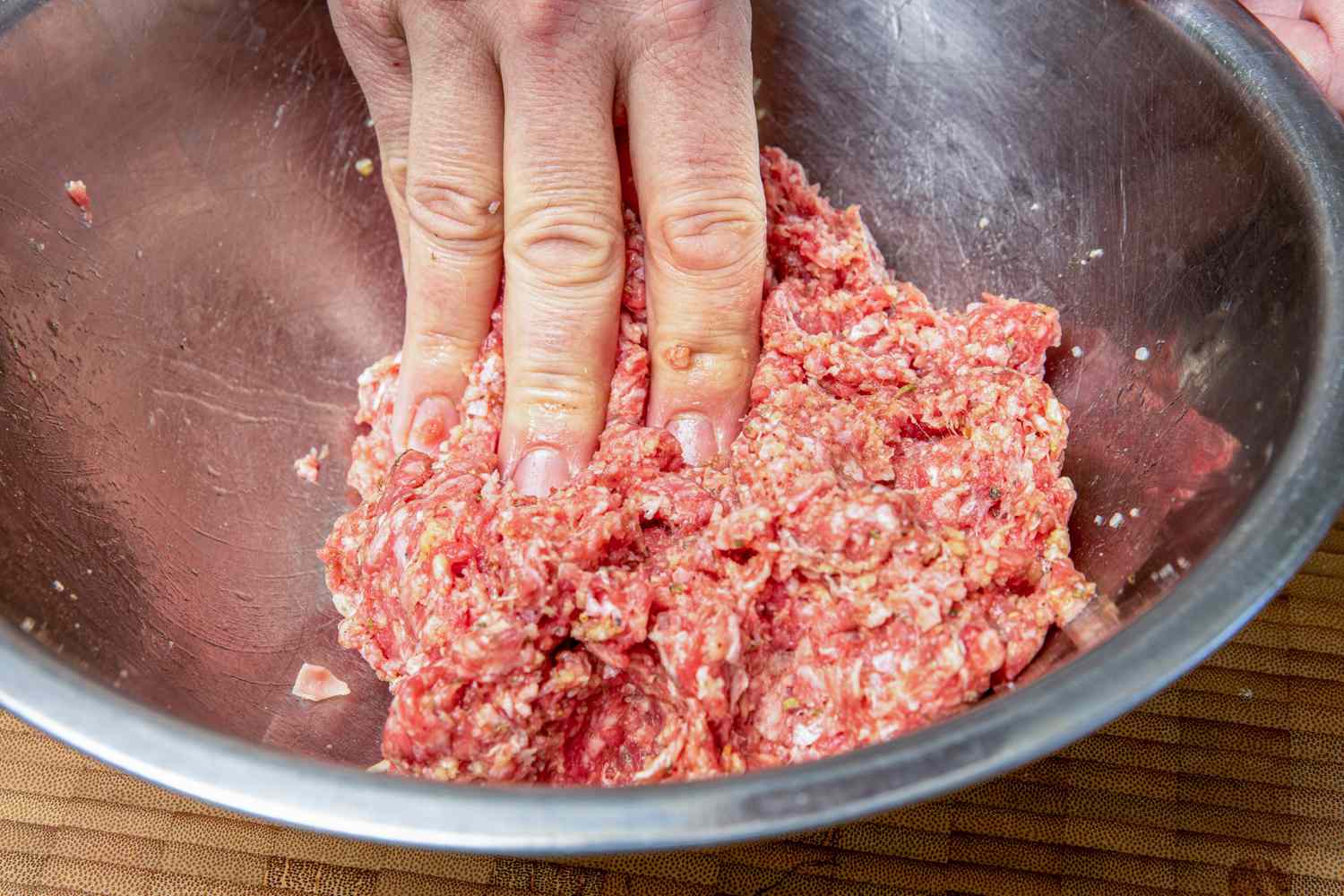 A Hand Mixing Grilled Greek Meatballs Ingredients Together in a Bowl 