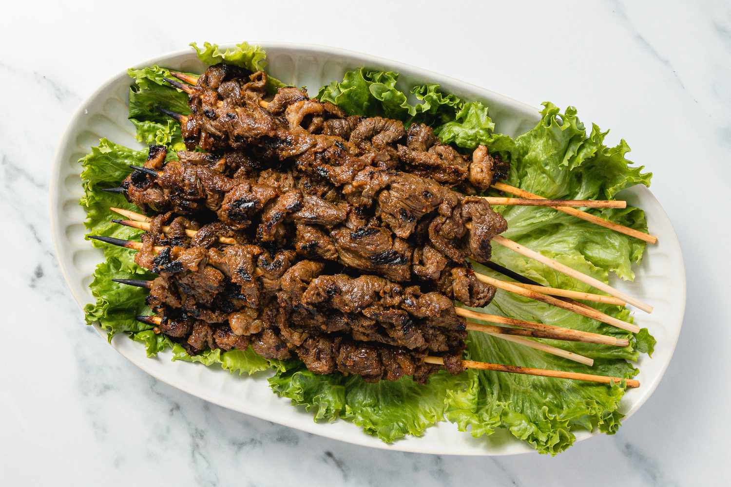 Cambodian Grilled Lemongrass Beef Skewers on a Green Lettuce Lined Platter