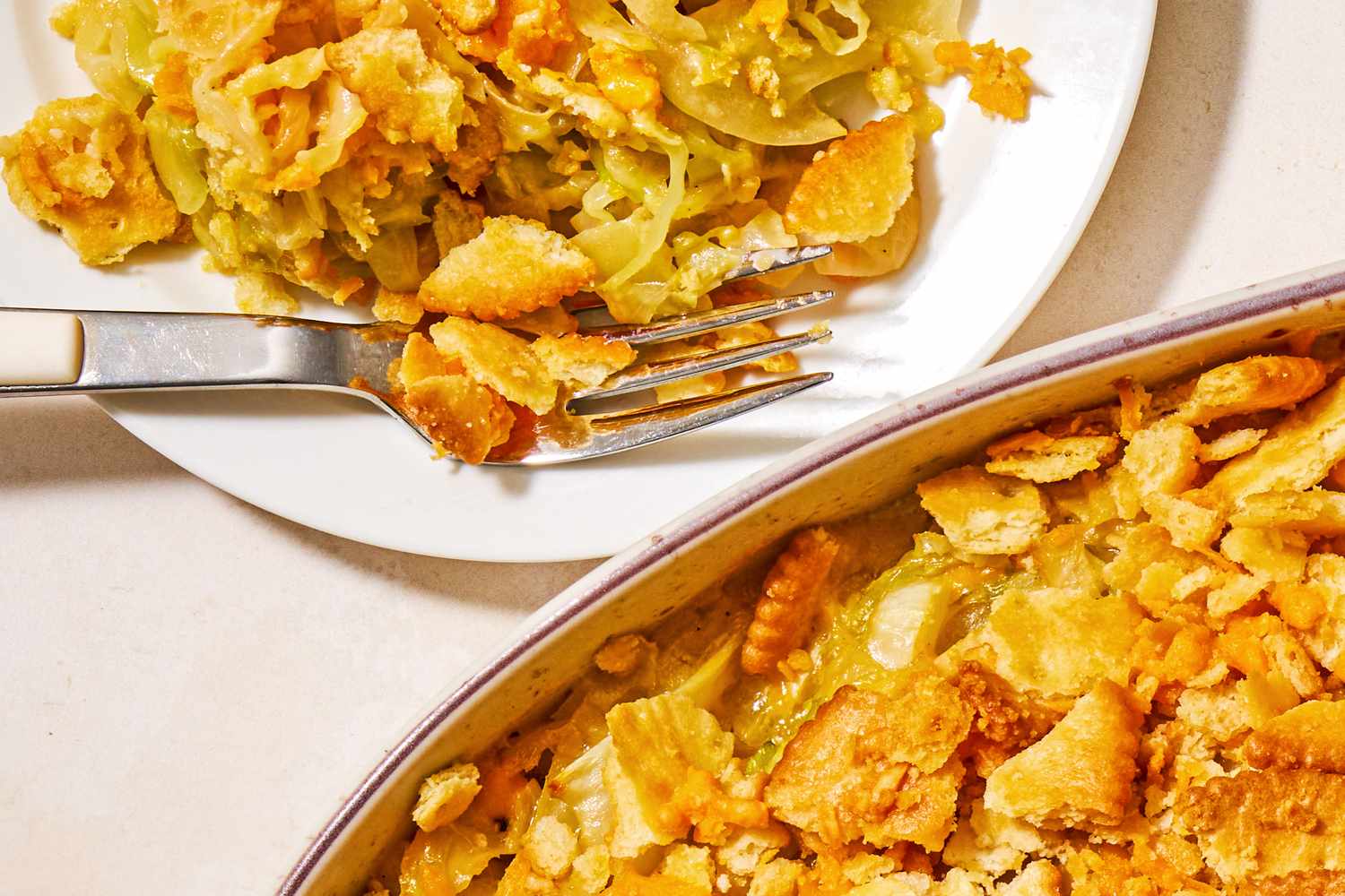 Cheesy cabbage casserole topped with crispy crackers served on a plate with a fork and in a baking dish