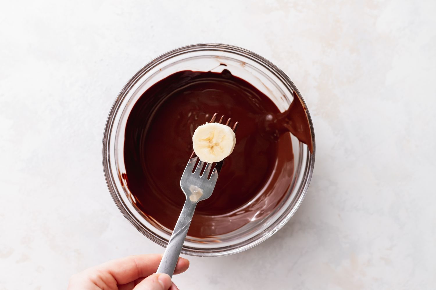 Banana Slice on Fork Above a Bowl of Melted Chocolate for Frozen Chocolate Bananas