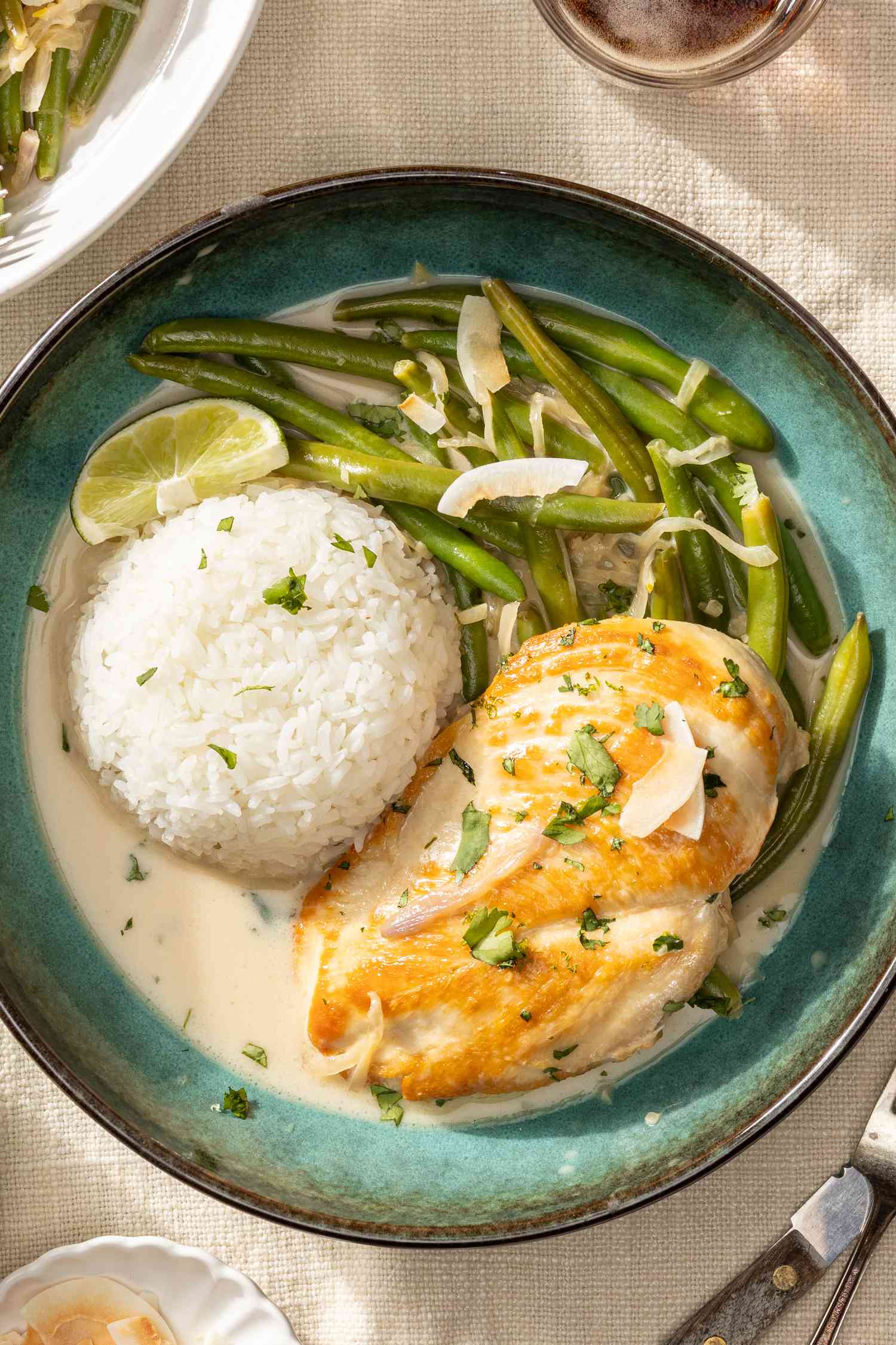 creamy coconut lime chicken on a plate with rice at a table 