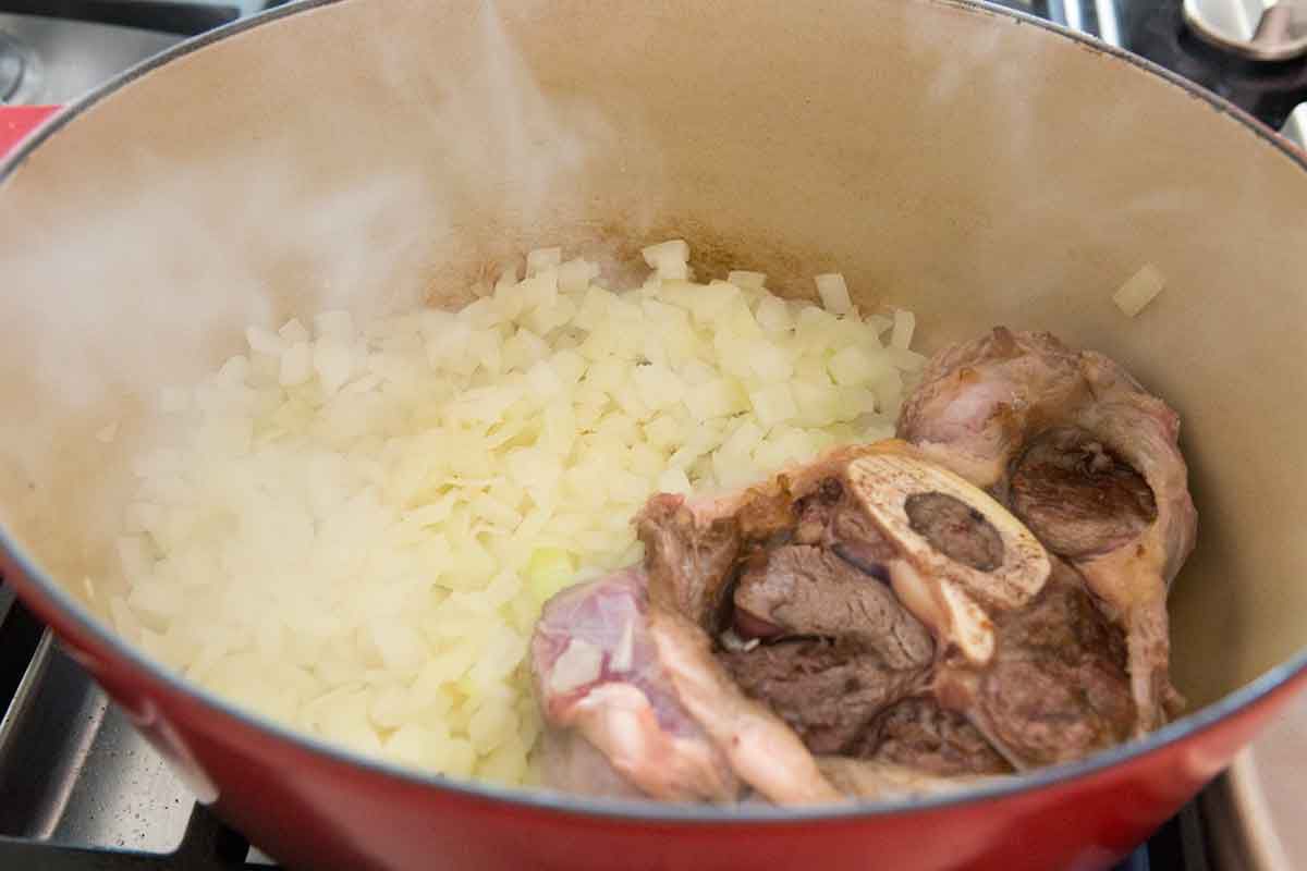 Onions and a beef shank cooking in a Dutch oven