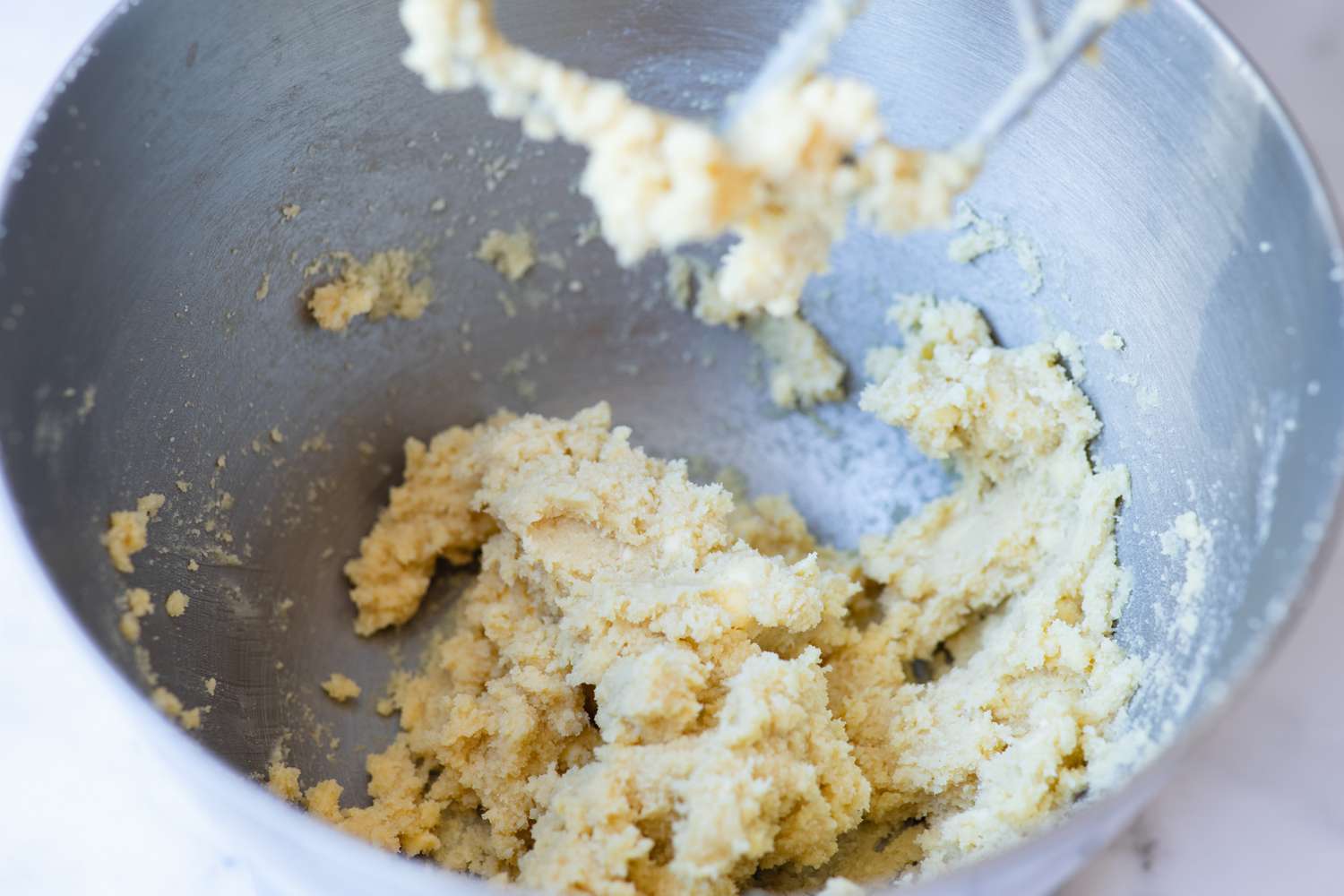 Creaming ingredients in a bowl to make an almond cookie recipe.