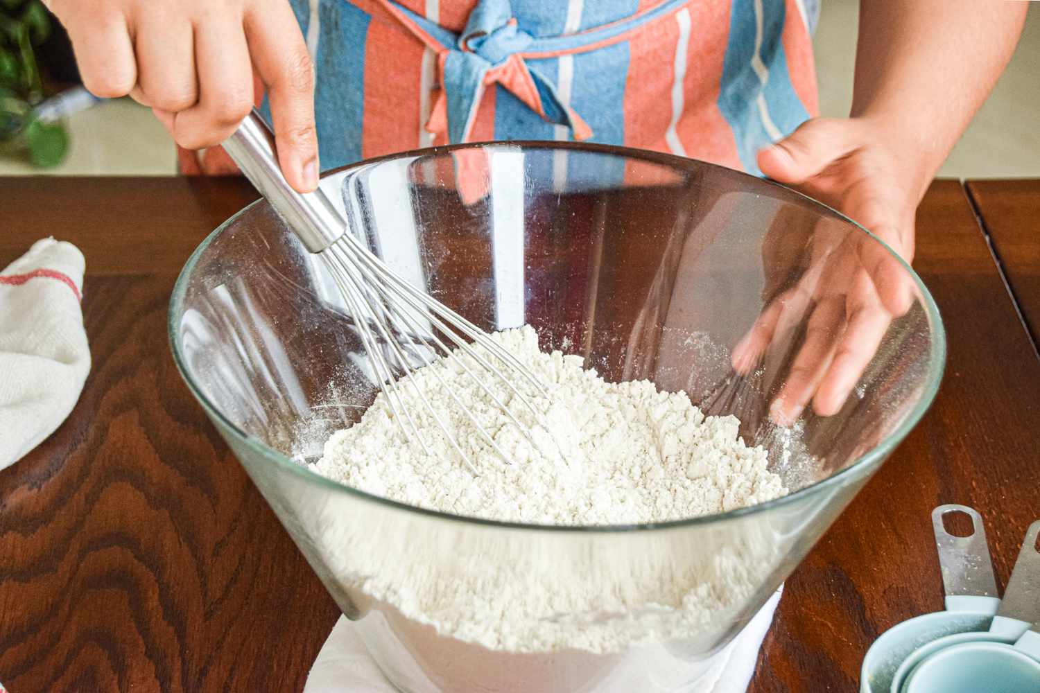 Whisking flour mixture in a bowl to make a hummingbird cake recipe.