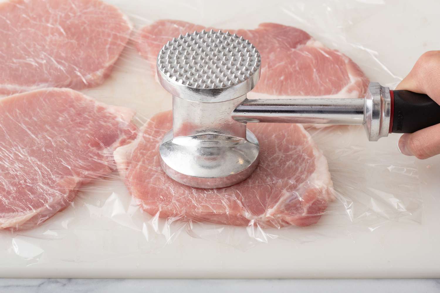 Pounding pork cutlets to make a schnitzel recipe.