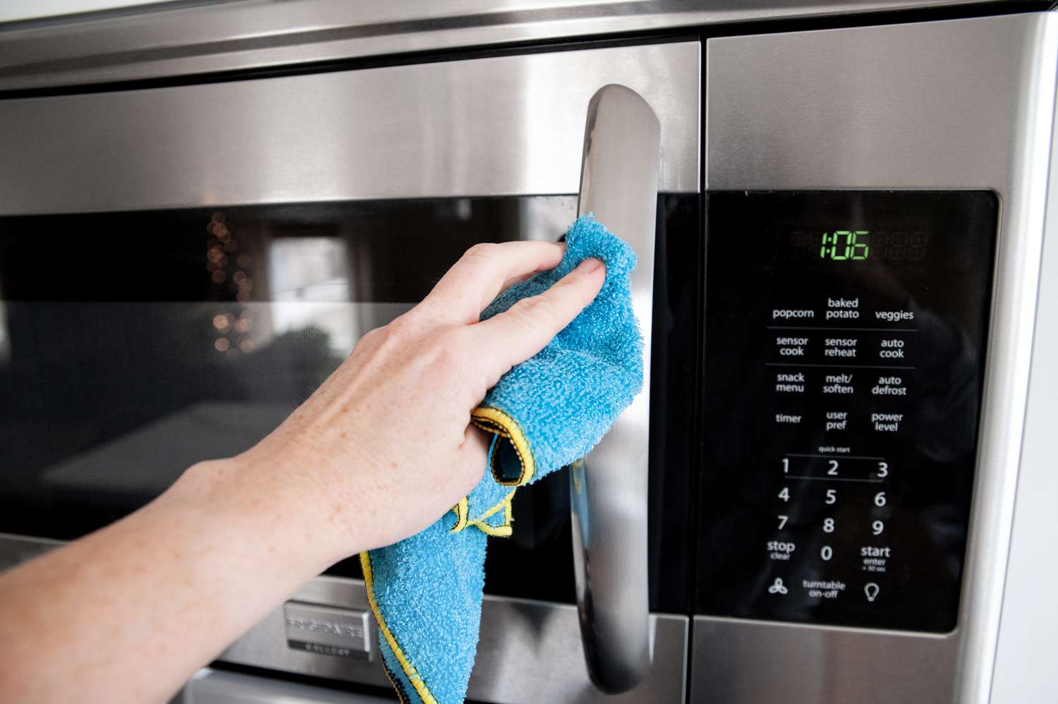 Hand Wiping the Exterior of a Mounted Microwave 