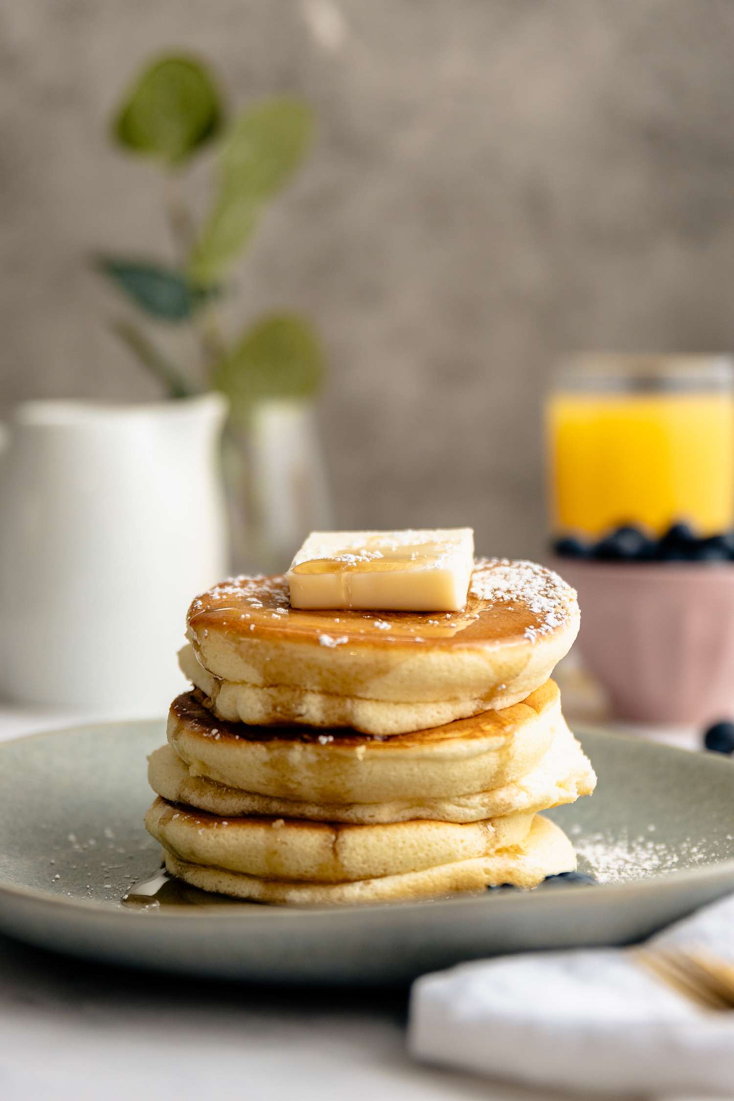 Japanese Souffle Pancakes Topped with Butter, Maple Syrup, and Powdered Sugar on a Plate