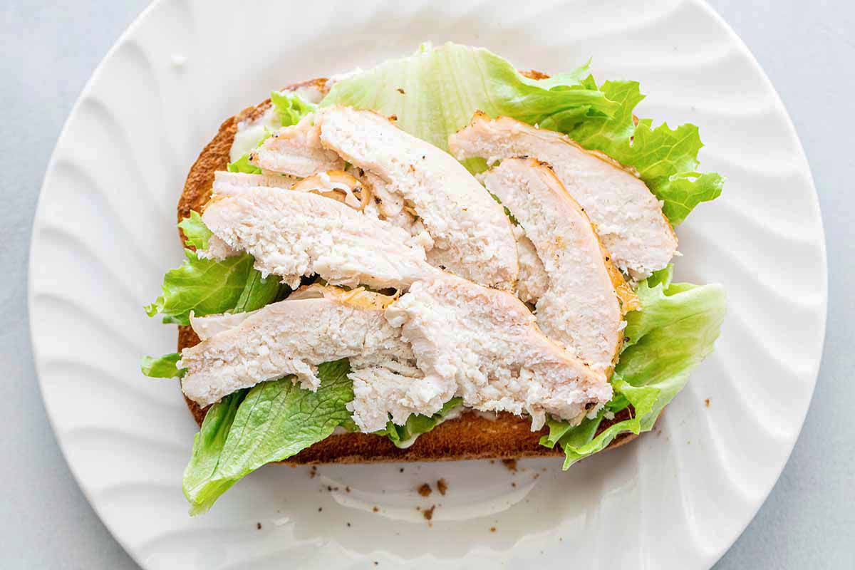 Turkey club with garlic mayo with roast turkey and lettuce on top of a toasted piece of bread.