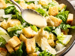 Caesar dressing spooned onto a caesar salad