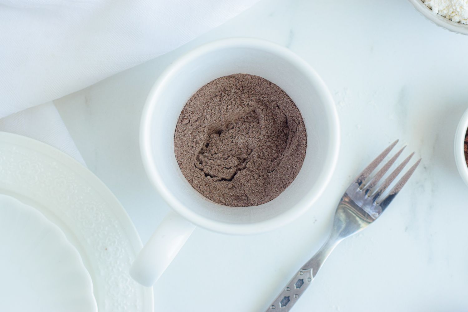 Cocoa in the bottom of a mug with a fork next to it.