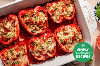 Stuffed bell peppers filled with a mixture of cooked ingredients topped with melted cheese in a baking dish labeled Simply Recipes