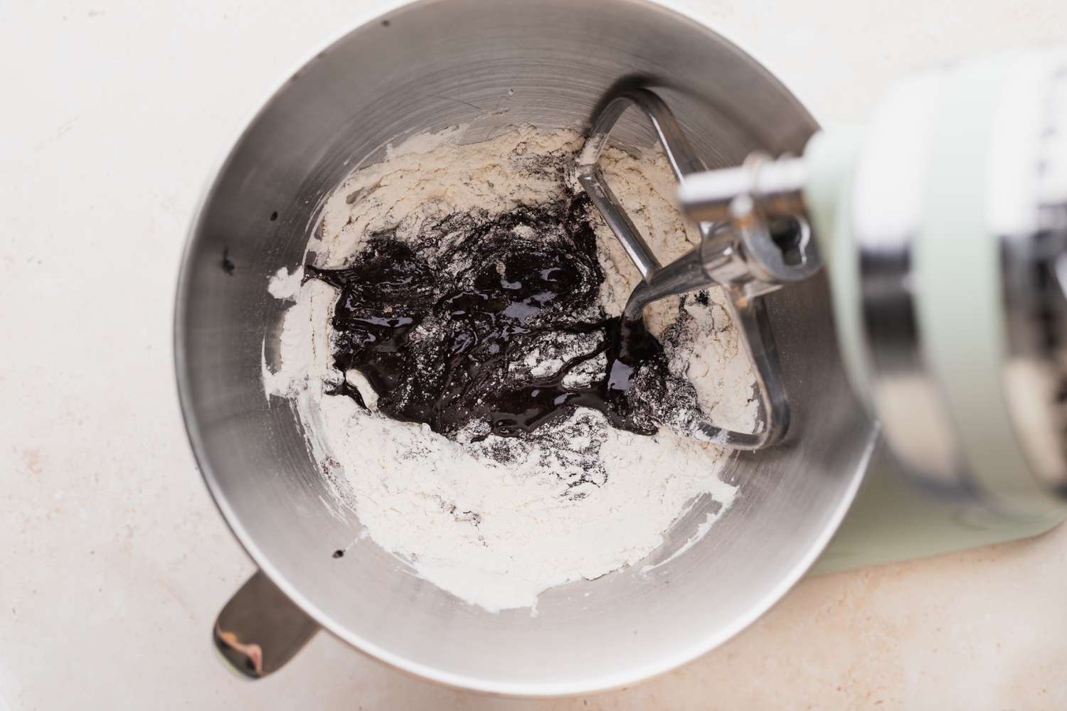 Adding dry ingredients to the bowl of a stand mixer to make chocolate christmas cookies.