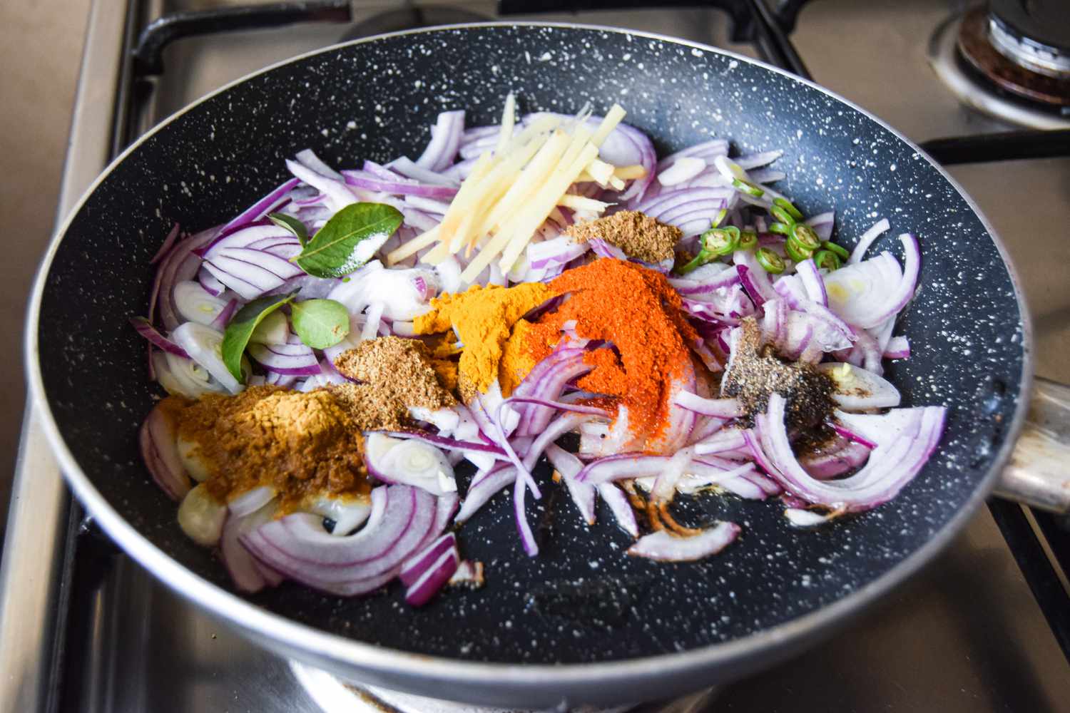 Onions, Ginger, Curry Leaves, and Spices Added to Skillet on the Stove with Melted Ghee for Egg Curry Recipe