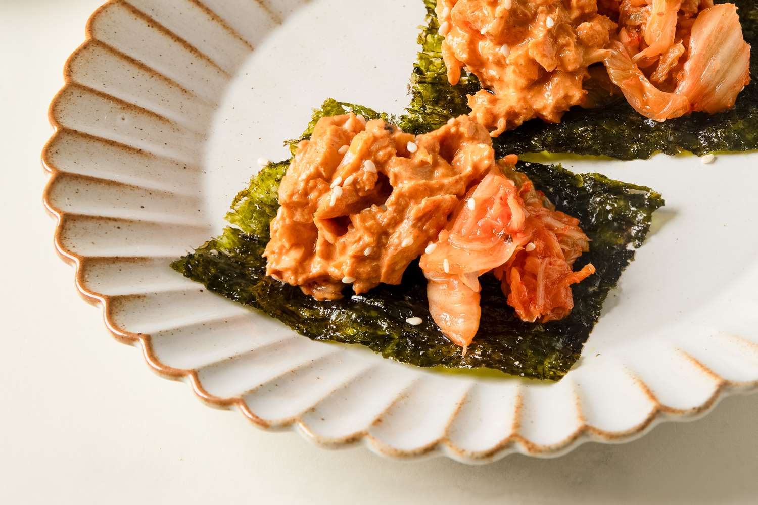Gochujang tuna salad served on a seaweed wrap with kimchi on a plate