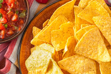 A close-up of tortilla chips in a bowl next to a bowl of salsa