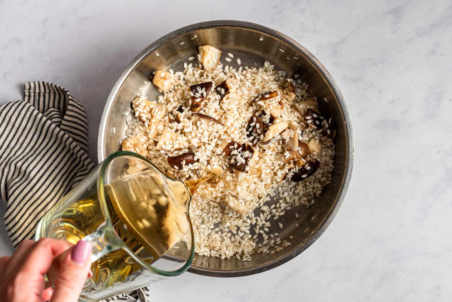 Adding brandy to a pot holding rice and mushrooms