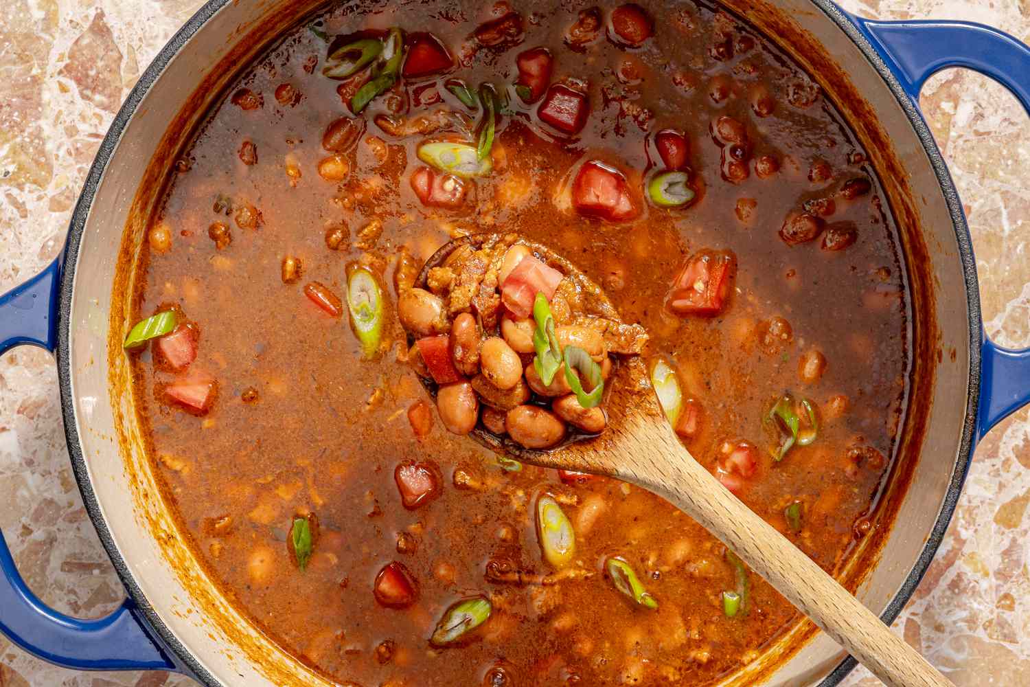 Borracho beans in a blue pot with a wooden spoon