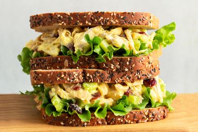 Triplelayered sandwich made with seeded bread lettuce and a creamy filling placed on a wooden surface