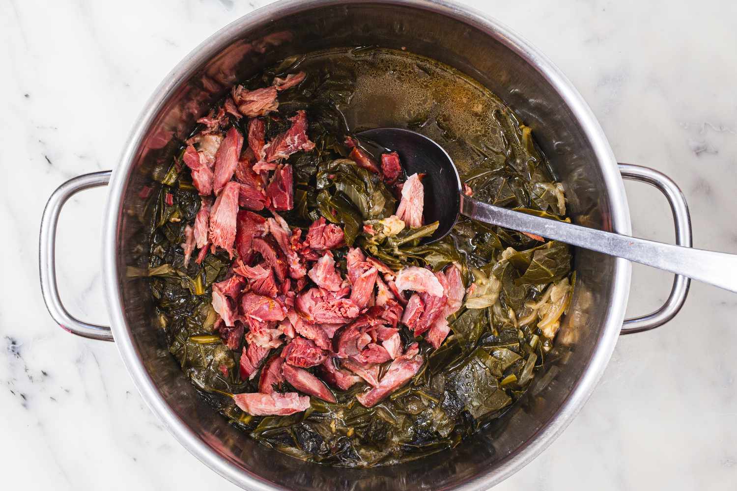 Adding the chopped ham into a stockpot to make pot liquor.