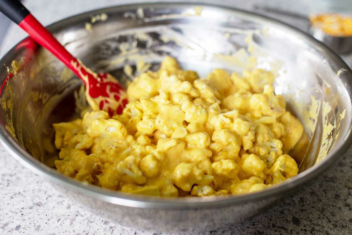 A metal bowl with Vegetarian Cauliflower Casserole being stirred together.