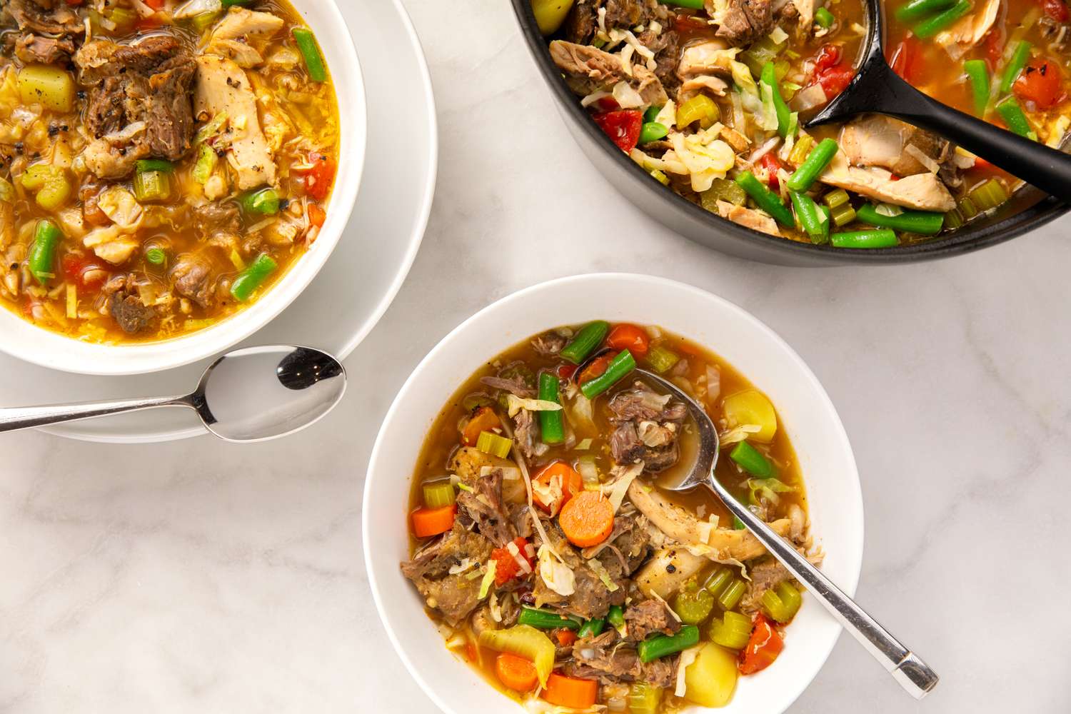 Three bowls of stew with vegetables and meat served in bowls with spoons alongside a pot