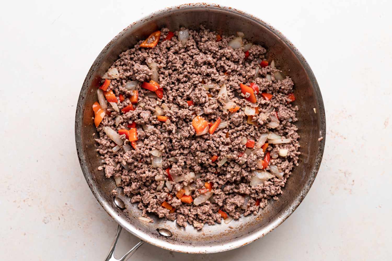 Beef, onions, and tomatoes in a skillet to make a lasagna recipe.