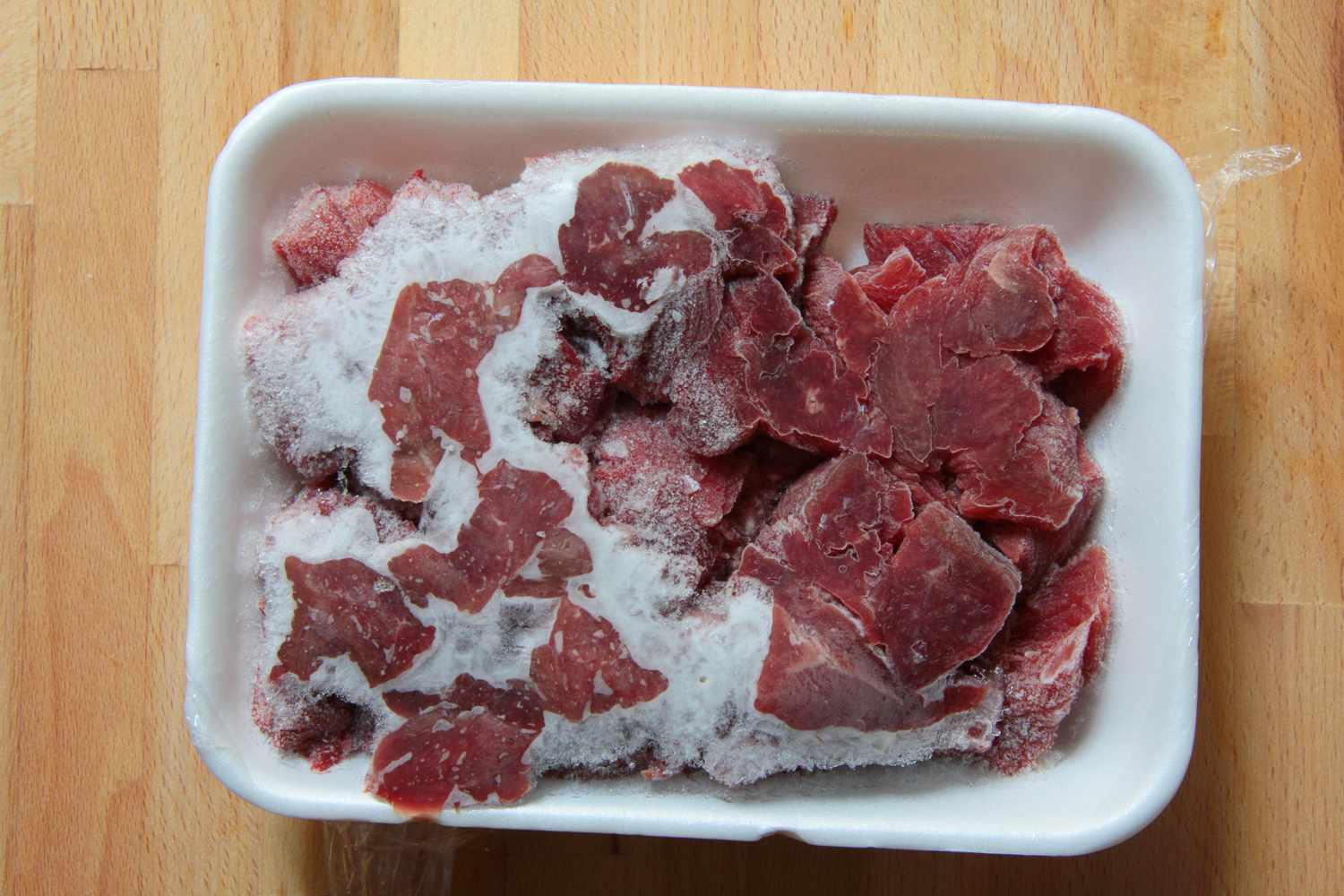 a frozen package of beef stew meat with freezer burn