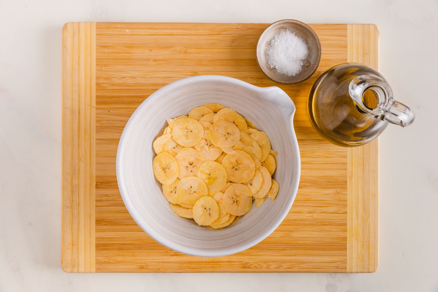 Sliced Plantains in a Bowl Next to a Bowl of Salt and Olive Oil