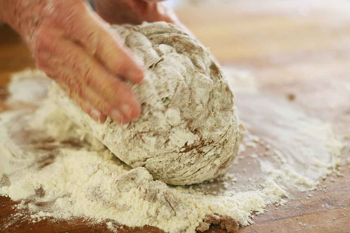 Kneading rye bread dough on a wooden table dusted with flour