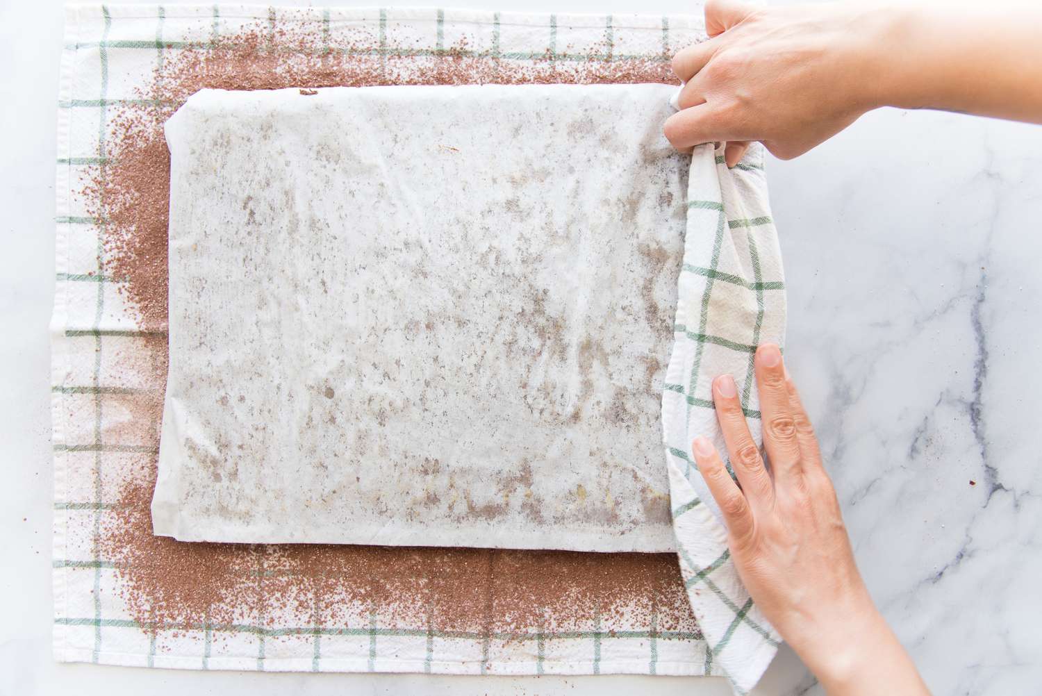 Using a tea towel to roll up a chocolate swiss roll.