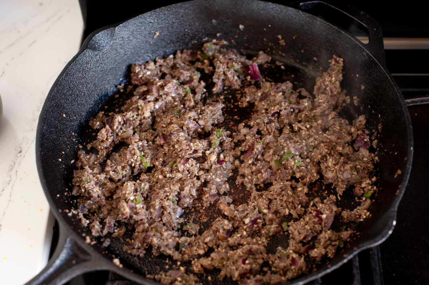 Cooked Minced Vegetables in a Cast Iron Skillet for Black Bean Smash Burger Recipe