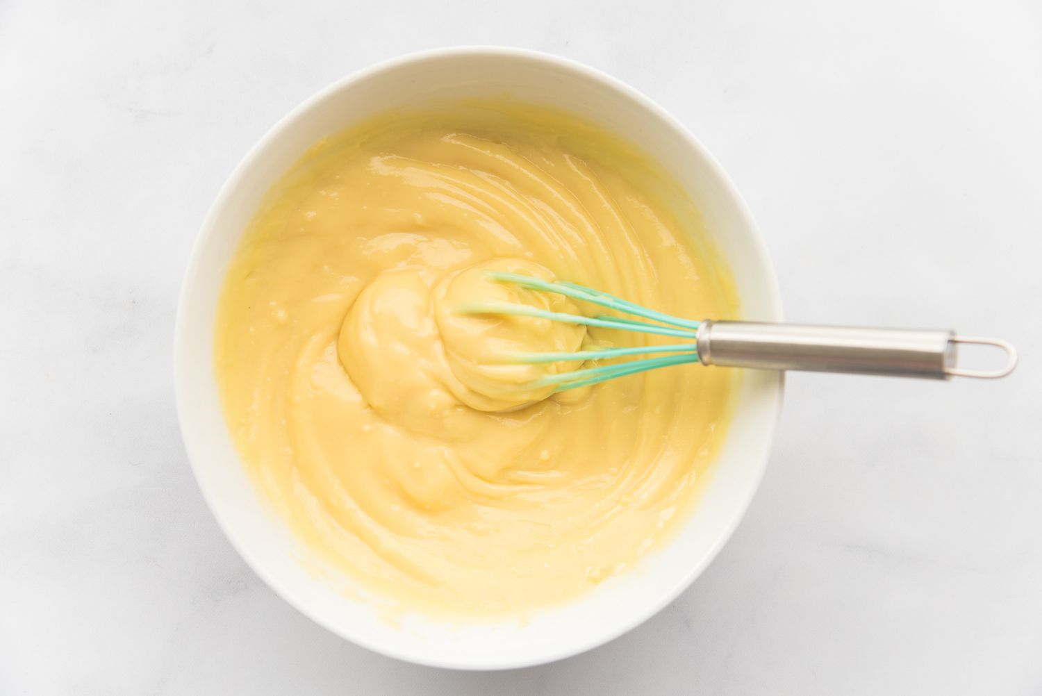 A bowl with a whisk to show how to make German buttercream frosting.