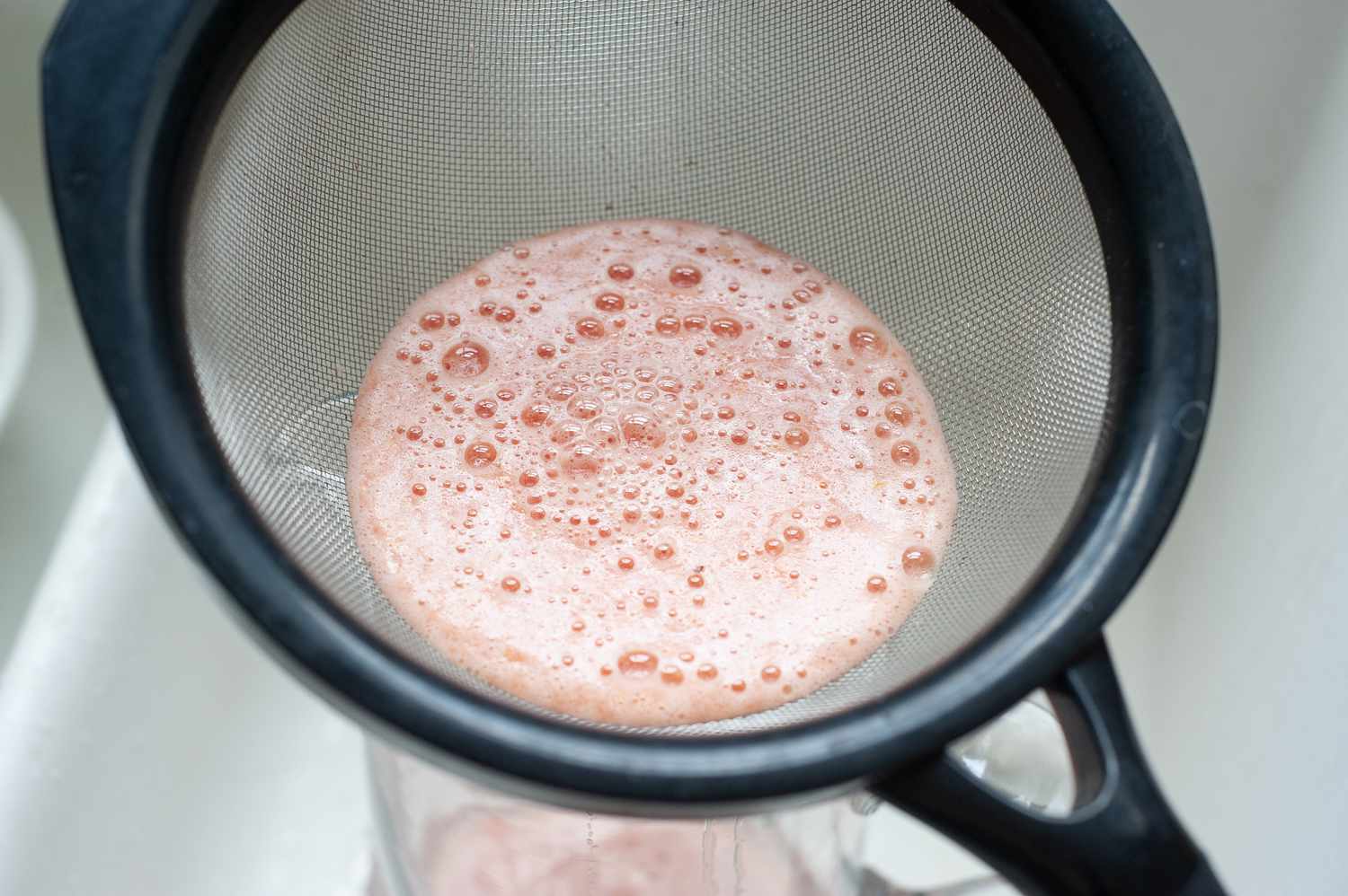 Whole lemon watermelon lemonade strained into a pitcher.