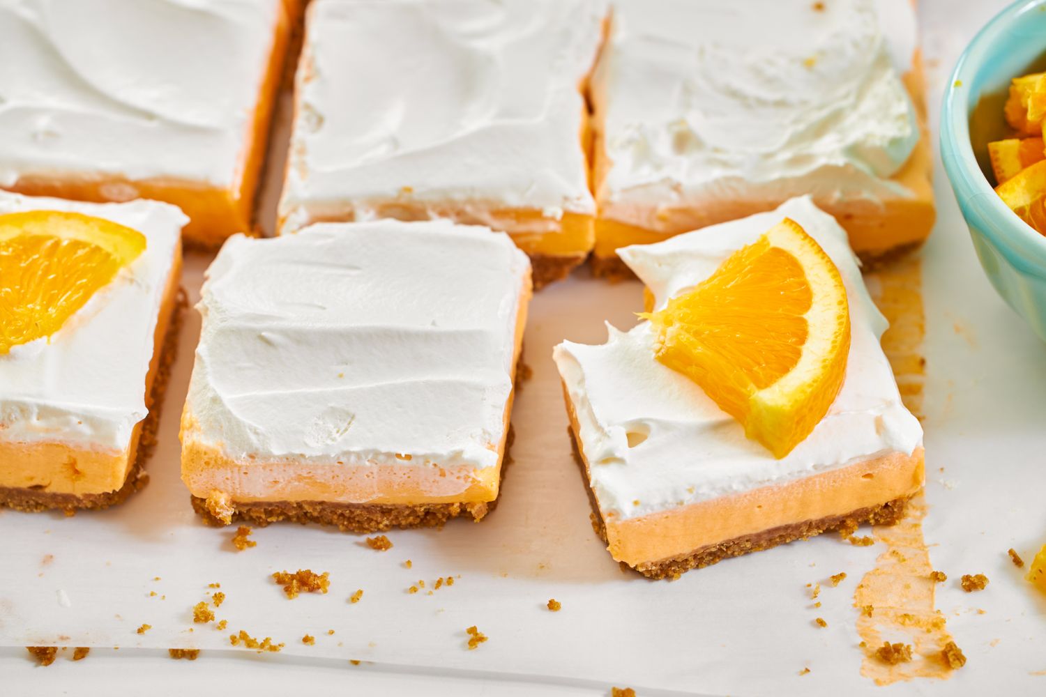 Creamsicle dessert bars topped with whipped cream and orange slices