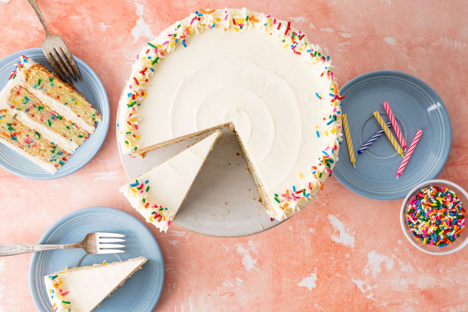 Confetti Cake Surrounded by Cake Slices on Small Plates and a Bowl of Sprinkles