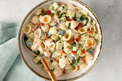 A bowl of pasta salad with bacon cucumber and ranch dressing with a fork
