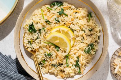 Overhead shot of a plate with lemony spinach rice, topped with two lemon slices