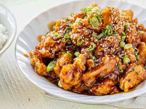 Bowl of Chinese Orange Chicken Next to a Bowl of Rice 