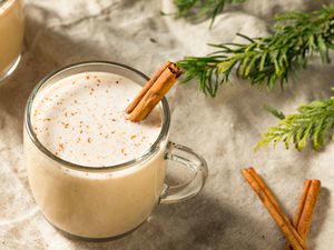 A cup of eggnog with a cinnamon stick