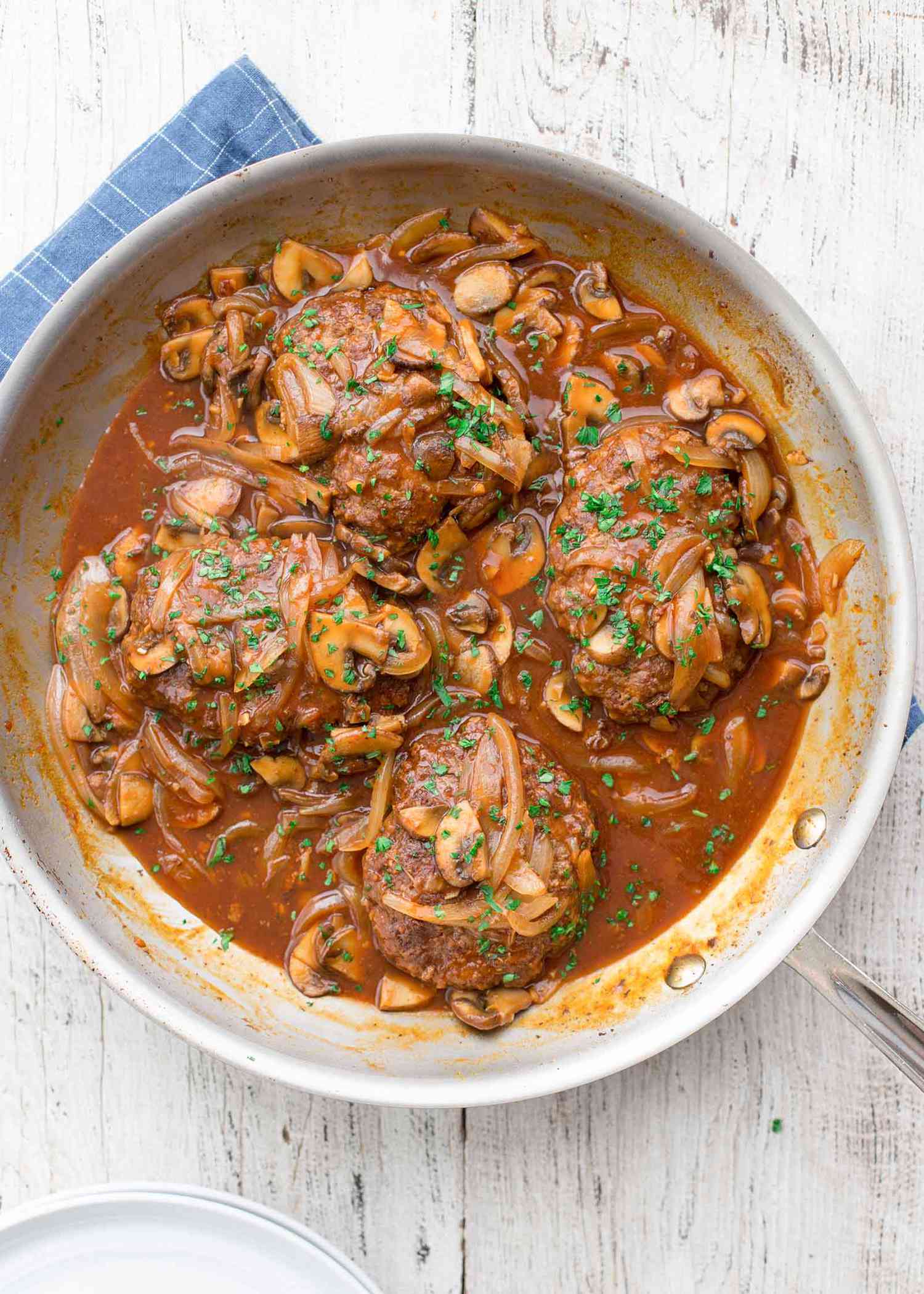 Four homemade salisbury steaks in a pan