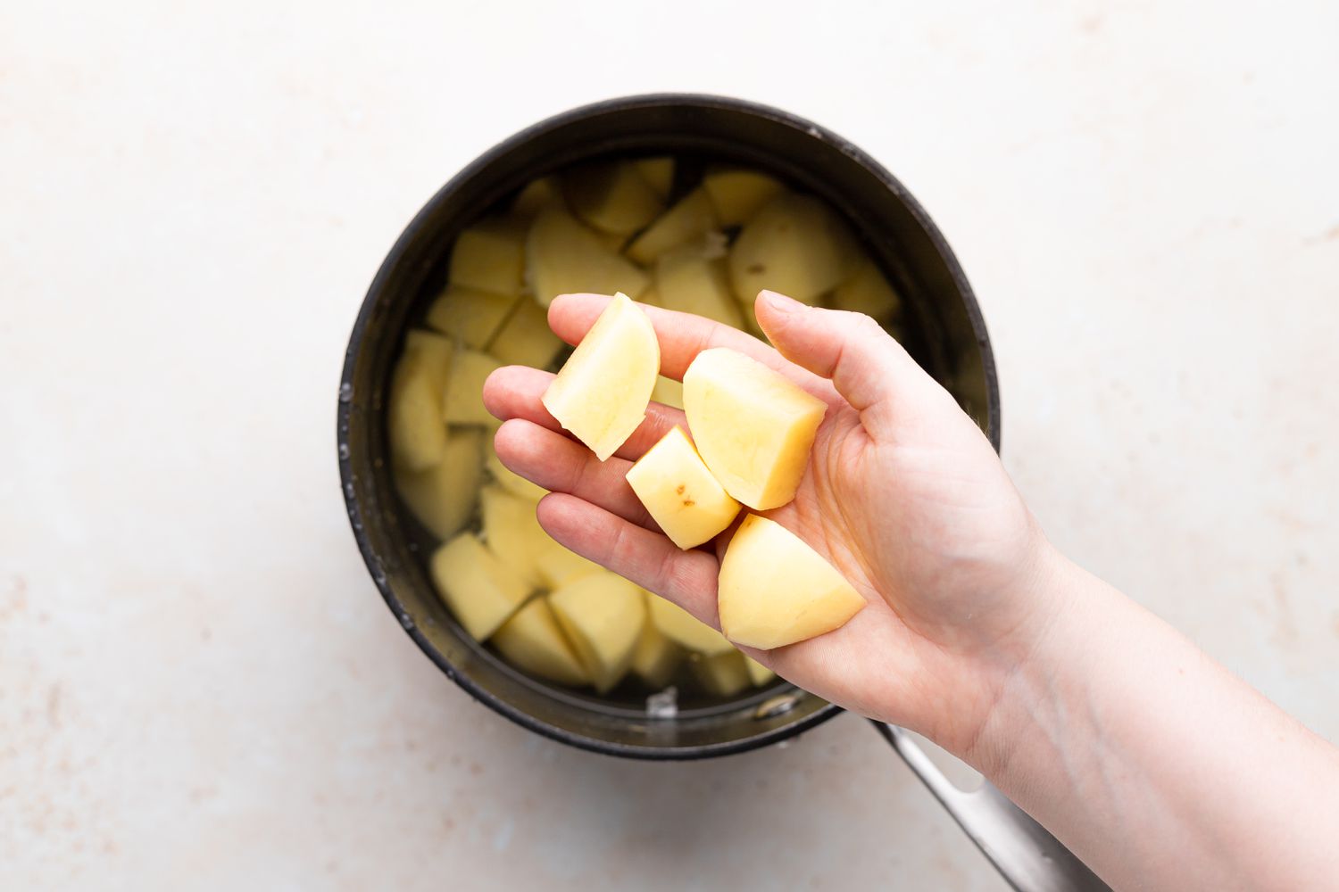 Adding cubed potatoes to a pot of water.