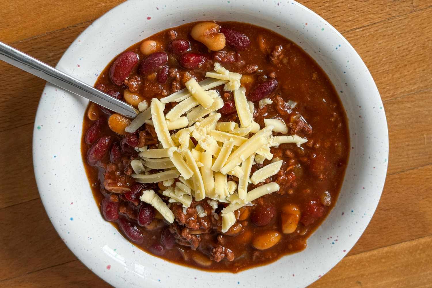 Bowl of chili topped with shredded cheese and a spoon