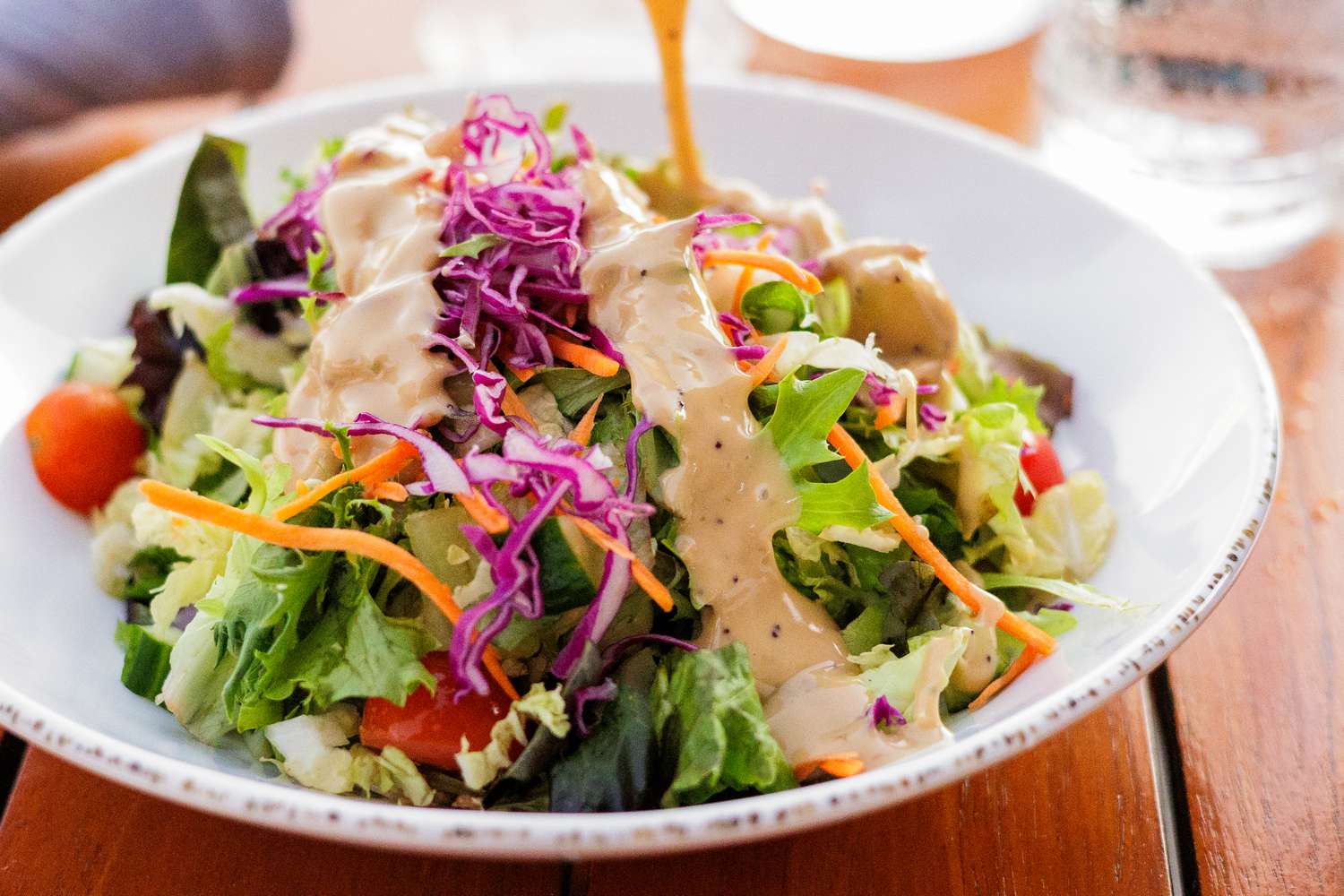 Close up of a salad with dressing being poured on it