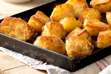 roasted potatoes in a sheet pan over a kitchen towel on the counter