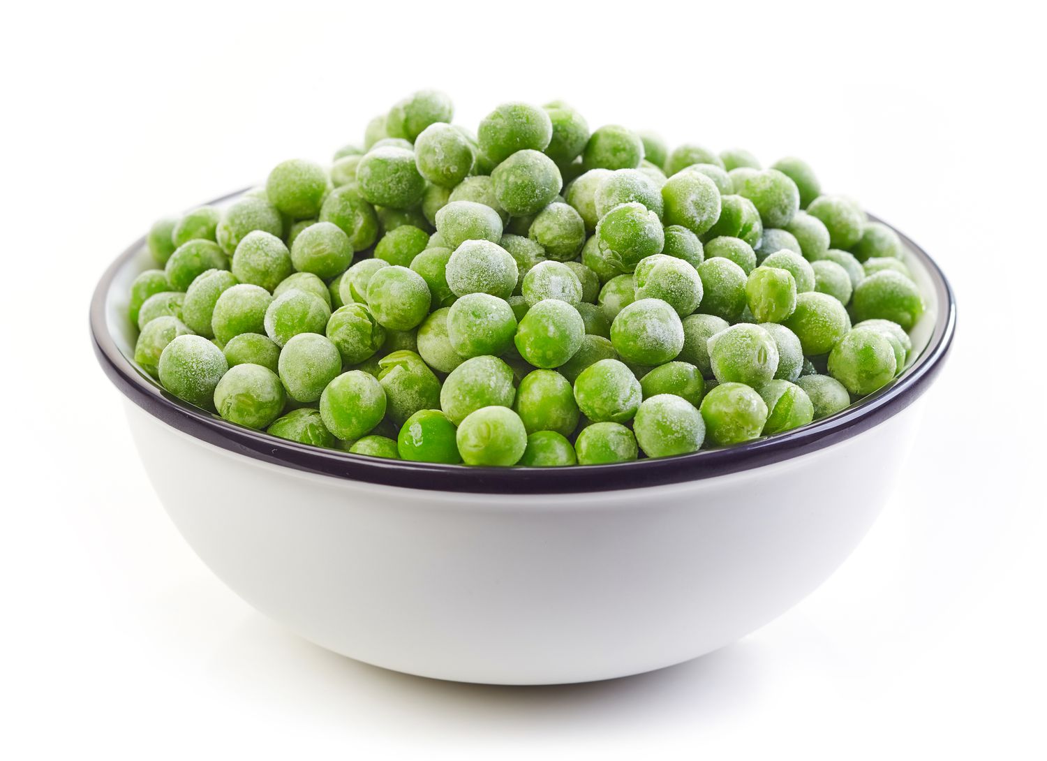 Side view of a white bowl full of frozen peas on a white background