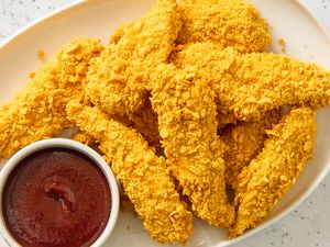 Plate of crispy chicken tenders with a small bowl of dipping sauce