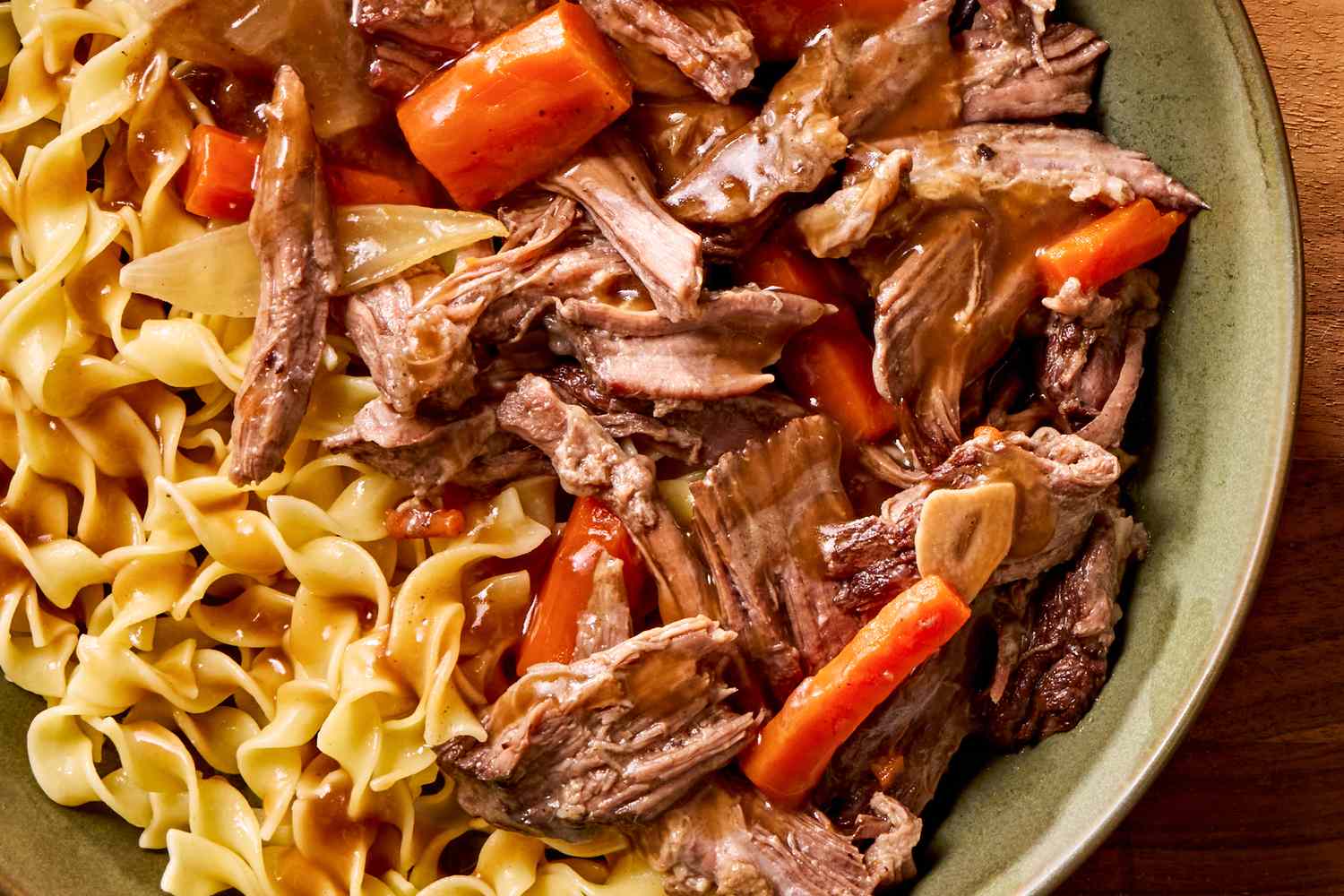 Pot roast with carrots and egg noodles served on a plate