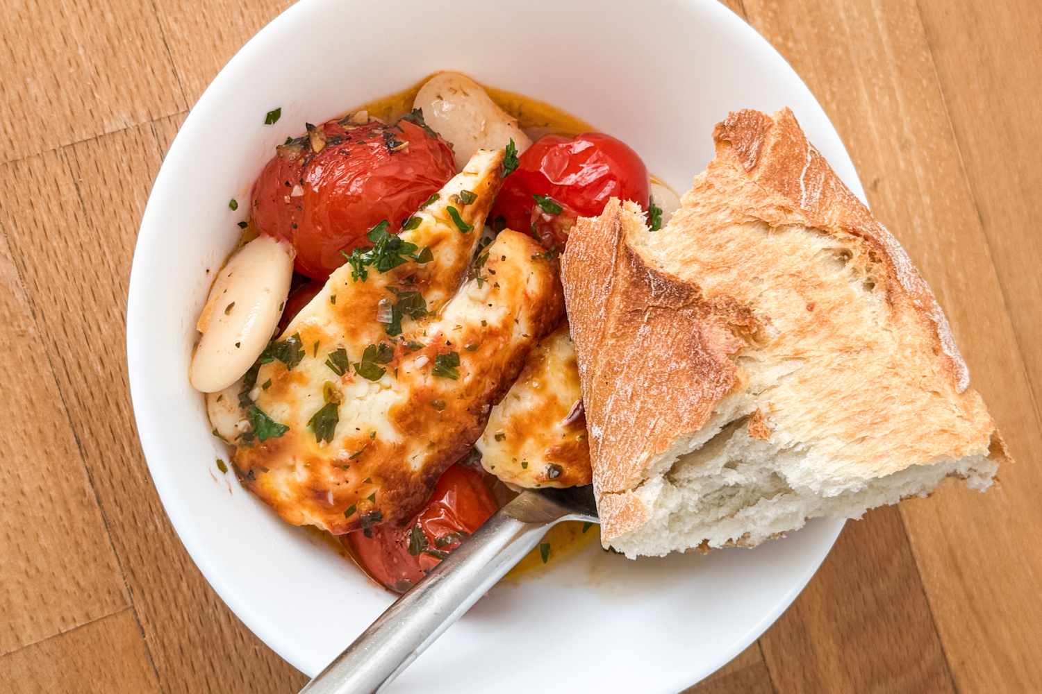 Bowl of food containing grilled chicken beans cherry tomatoes and a piece of bread for Crispy Halloumi With Tomatoes and White Beans
